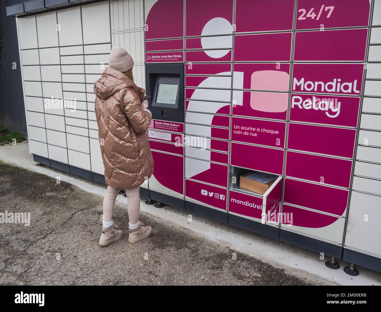 Loriol sur Drome, Frankreich - 14. Januar 2023: Abholung eines Pakets aus einem Mondial`Relay-Schließfach durch eine junge Frau. Schließfächer Mondial Relay. Pickup-Box. Stockfoto